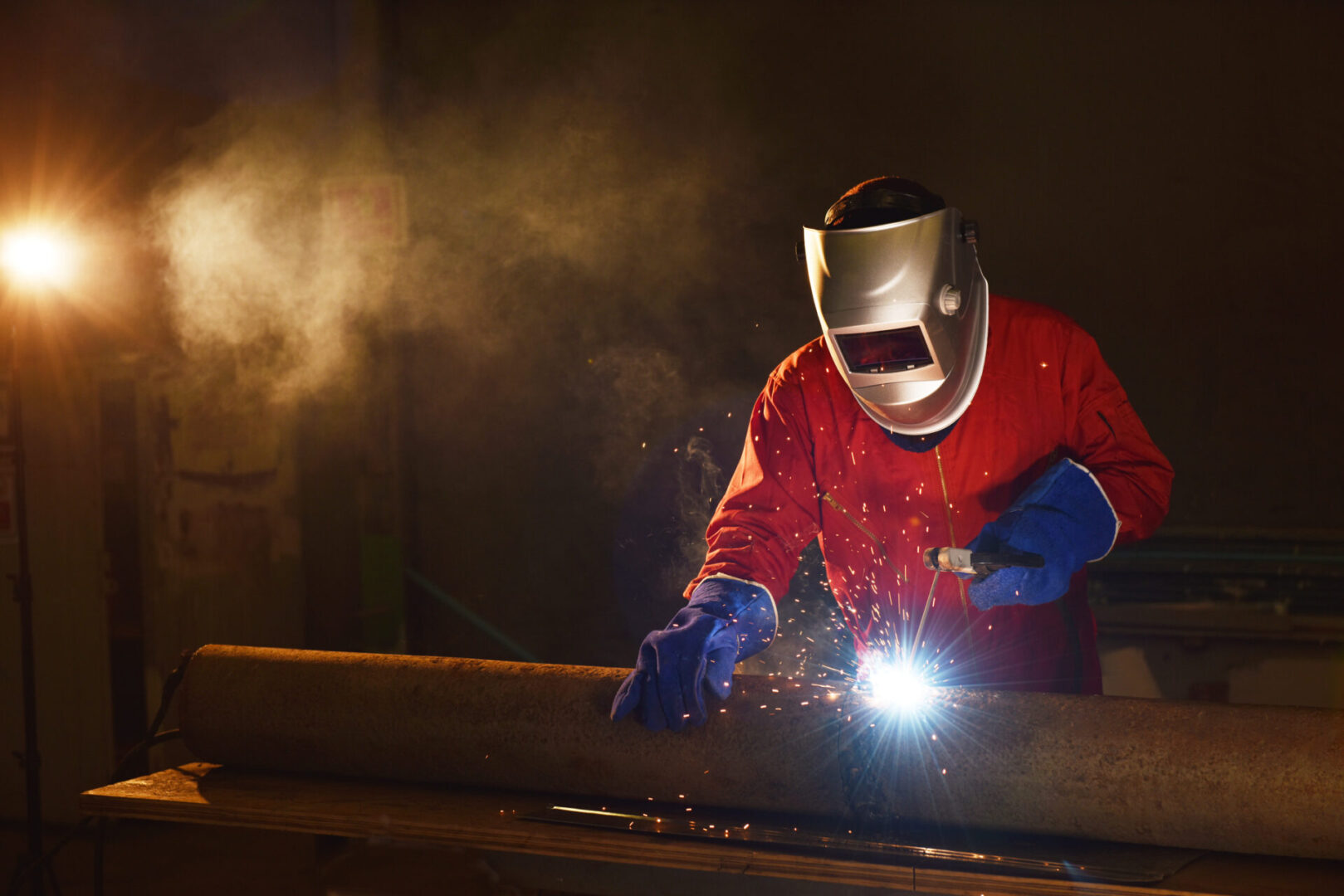 Welder in workshop wearing helmet and working